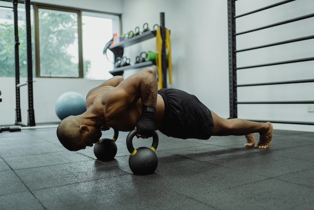 man doing push-ups on dumbbell